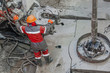 Work driller in red uniform, in helmet and goggles. He uses a hydraulic wrench to screw drill pipes to lower them into an oil well and continue drilling it. The concept of a working person.
