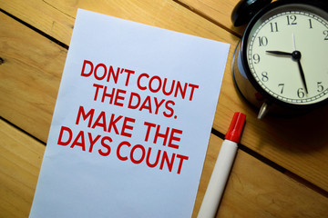 Wall Mural - Don't Count The Days. Make The Days Count text on the paper isolated on table background