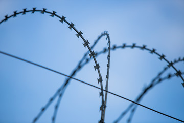 Barbed wire fence around prison walls blue sky in background