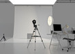 © Corona Borealis - Empty modern photo studio interior with professional lighting equipment, soft box lights, reflectors, camera, tripods, computer, white backdrop