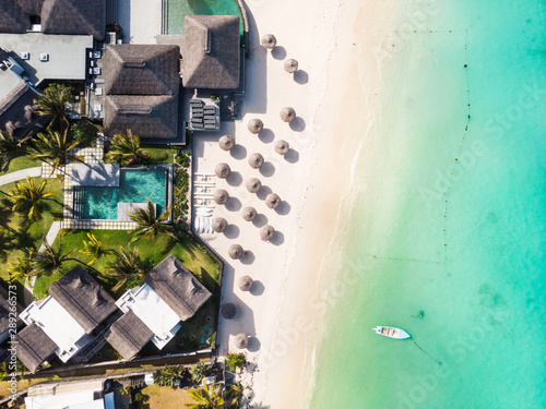 Fotomural Aerial view of beautiful tropical beach front hotel resort with swimming pool, palm leaves umbrellas and turquoise sea