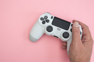Wall Mural - Video games man playing white gaming controller in hands isolated on pink color background top view