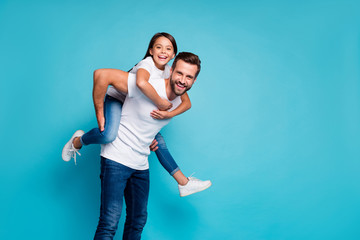 Poster - Portrait of cheerful people laughing piggyback wearing white t-shirt denim jeans isolated over blue background