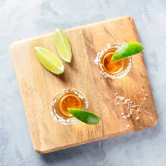 Wall Mural - Golden tequila shots with lime slices and salt rims, overhead square shot