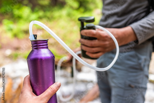 Fotografía Man and woman couple using water filter on hiking trail river in Colorado to pur