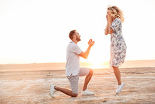 Photo Of Happy Man Making Proposal To His Excited Woman With Ring While Walking On Sunny Beach