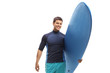 Young male surfer holding a surfboard and smiling at the camera