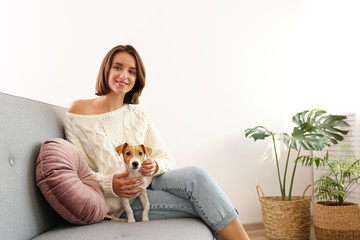 Portrait of young beautiful hipster woman with her adorable four months old jack russell terrier puppy at home in living room full of natural sunlight. Lofty interior background, close up, copy space.