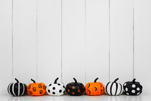 Black, White And Orange Patterned Halloween Pumpkins In A Row Against A White Wood Background. Copy Space.