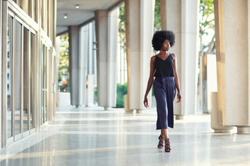 A young fashionable Afro-American woman confidently walking down the hall outside the financial building