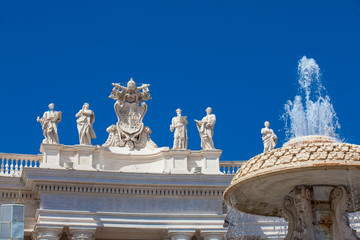 Wall Mural - Fountain and detail of the Chigi coats of arms and the statues of saints that crown the colonnades of St. Peter Square built on 1667 on the Vatican City