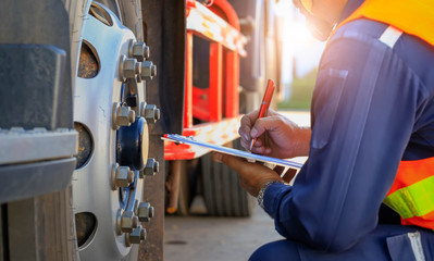 Preforming a pre-trip inspection on a truck,Concept preventive maintenance truck checklist,Truck driver holding clipboard with checking of truck,spot focus.