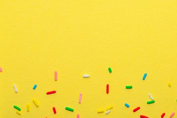 colorful sprinkles over yellow background, decoration for festive Valentines day, birthday, holiday and party time, copy space