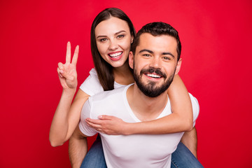 Wall Mural - Photo of two funny trendy casual fooling piggyback nice cute people together loving each other wearing jeans denim white t-shirt while isolated over red background