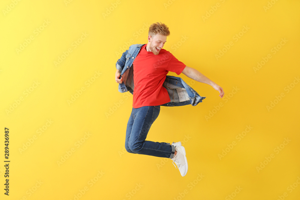 Handsome jumping young man against color background