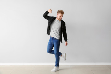 Wall Mural - Handsome young man dancing against light wall