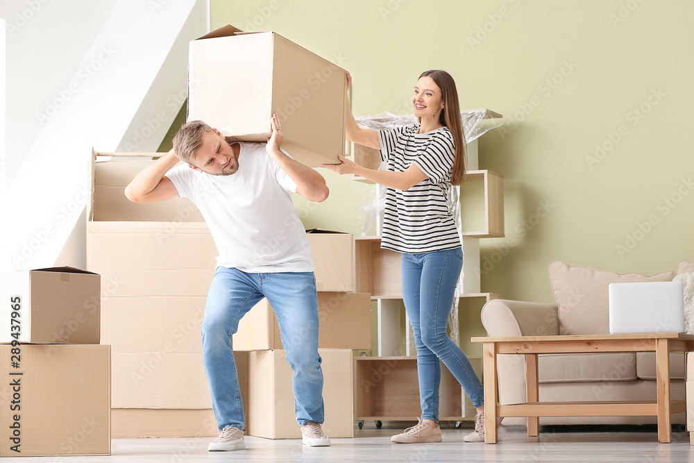 Young couple carrying boxes after moving into new house