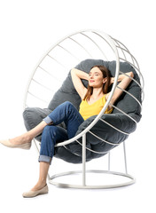 Wall Mural - Young woman relaxing in armchair against white background