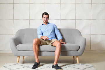 Wall Mural - Stylish man sitting on sofa indoors