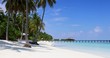 Tropischer Paradiesstrand auf den Malediven mit Palmen, türkisem Ozean und blauem Himmel