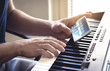 © terovesalainen - Man watching piano tutorial video with mobile phone. Person practising playing with an online lesson and course. Internet class to learn a new instrument. Pianist training with smartphone.