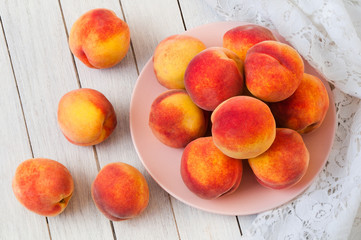 Wall Mural - Fresh organic peaches in a plate on a white wooden table