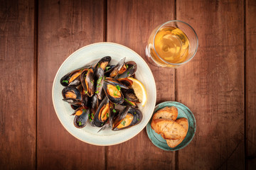 Wall Mural - Marinara mussels, moules mariniere, top shot on a dark rustic wooden background with toasted bread, a glass of wine, and a place for text