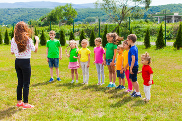 Wall Mural - Children with tutor play outdoor on the green lawn