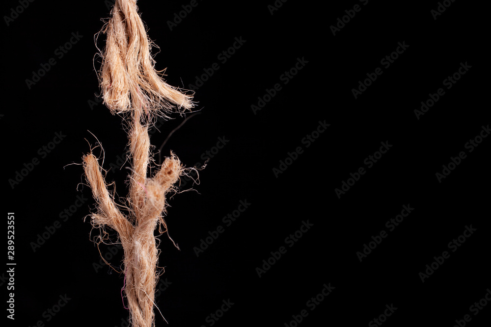 frayed rope ready to break on black background - obrazy, fototapety, plakaty 