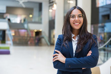 Young Businesswoman Smiling At Camera. Portrait Of Cheerful Hispanic Businesswoman In Formal Wear Standing With Crossed Arms And Looking At Camera. Business Concept