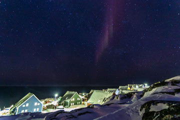 Wall Mural - Arctic polar night over colorful inuit houses with small northern light in a suburb of arctic capital Nuuk, Greenland