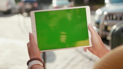 Close up hands woman using touch tablet device computer with green screen outdoors in street at sunlight horizontal message pad technology chroma key female digital girl app chat finger slow motion