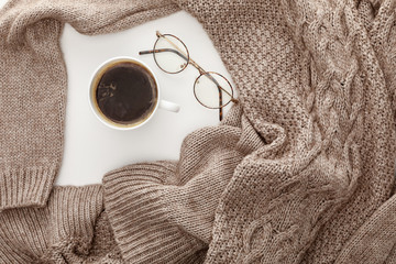 Wall Mural - top view of knitted brown sweater, coffee and glasses on white background