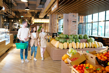 Poster - Casual young family of three moving down contemporary supermarket