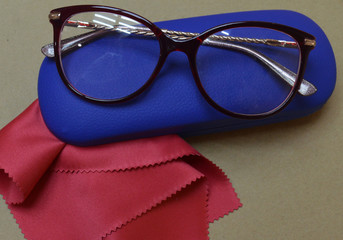 metal and plastic eyeglasses lie on the table along with eyeglass cases and napkins