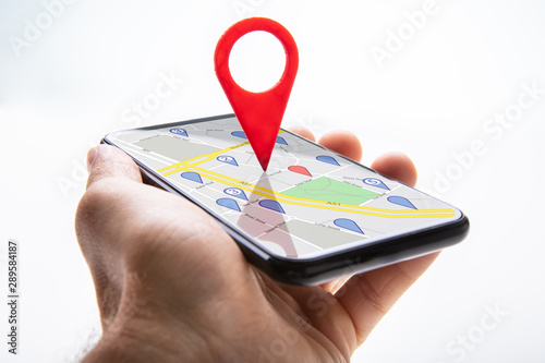 Fotografía Human Hand Holding Cellphone With Navigation Sign