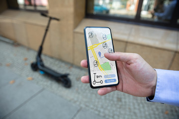 Young Man Using Electric Scooter Ride Sharing App