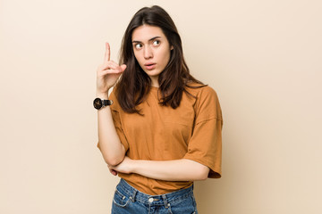 Wall Mural - Young brunette woman against a beige background having some great idea, concept of creativity.