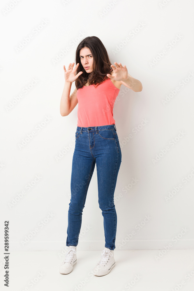 Full body young woman on white background being shocked due to an imminent danger - obrazy, fototapety, plakaty 