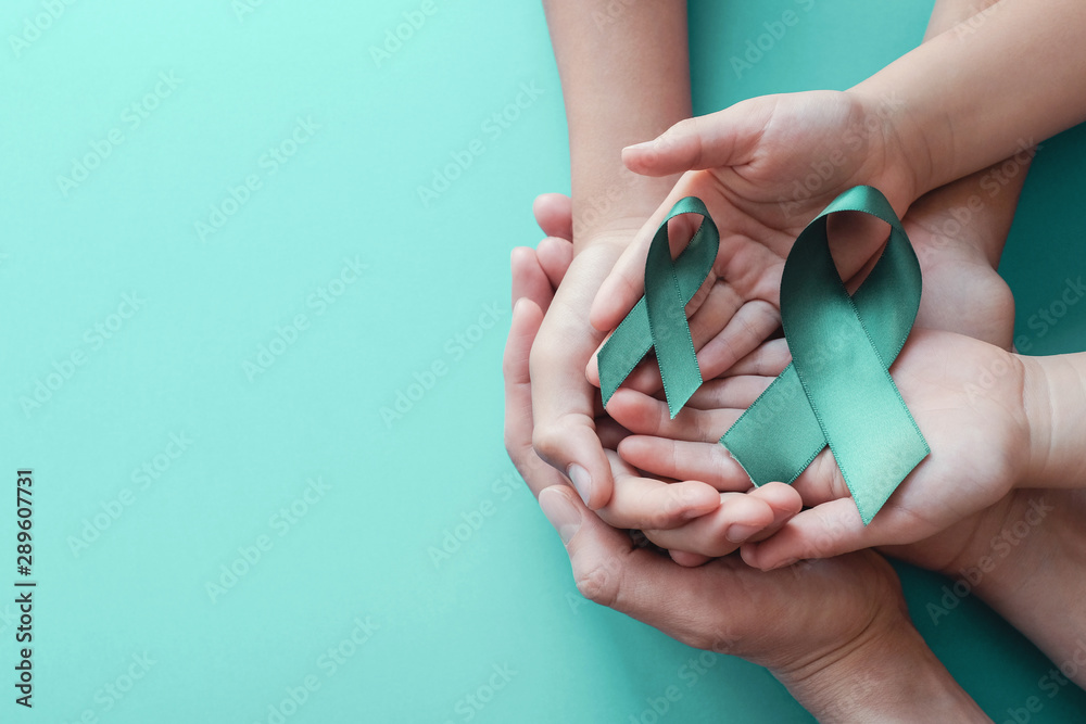 Adult and children hands holding Teal ribbons on blue background, Ovarian Cancer, cervical Cancer, anti bullying and sexual assault awareness - obrazy, fototapety, plakaty 