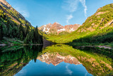 Fototapeta Góry - Maroon Bells lake at sunrise panoramic view in Aspen, Colorado with rocky mountain peak and snow in July 2019 summer and vibrant light reflection on water