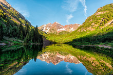 Maroon Bells Lake At Sunrise Panoramic View In Aspen, Colorado With Rocky Mountain Peak And Snow In July 2019 Summer And Vibrant Light Reflection On Water