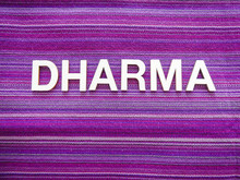 Wooden Text Letters With The Sanskrit Word "DHARMA" For A Sign, Banner, Placard Or Wallpaper On A Vibrant Purple Woven Texture Background