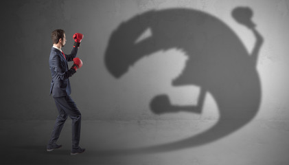 Wall Mural - Businessman with boxing glove fighting with a big monster shadow