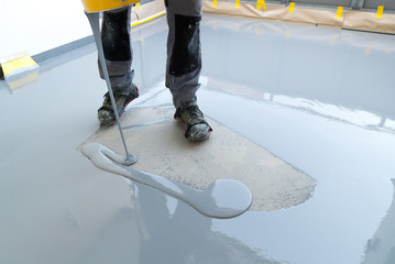 construction worker renovates balcony floor and pours watertight resin and glue before chipping and sealing