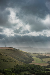 Wall Mural - Stunning Summer landscape image of escarpment with dramatic storm clouds and sun beams streaming down