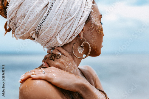Plakat close up of beautiful young tribal woman in turban at blue sea and sky background
