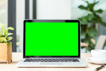 Mockup of laptop computer with empty screen with coffee cup on table of the coffee shop background,Green screen
