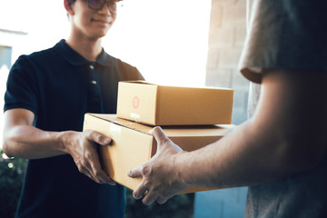 Close up of hands cargo staff are delivering cardboard boxes with parcels inside to the recipient's hand.