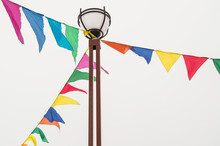 Colorful Triangular Cloth Flags Hanging On Ropes Tied To A Lamppost, Decoration For Festival, Carnival, Holiday